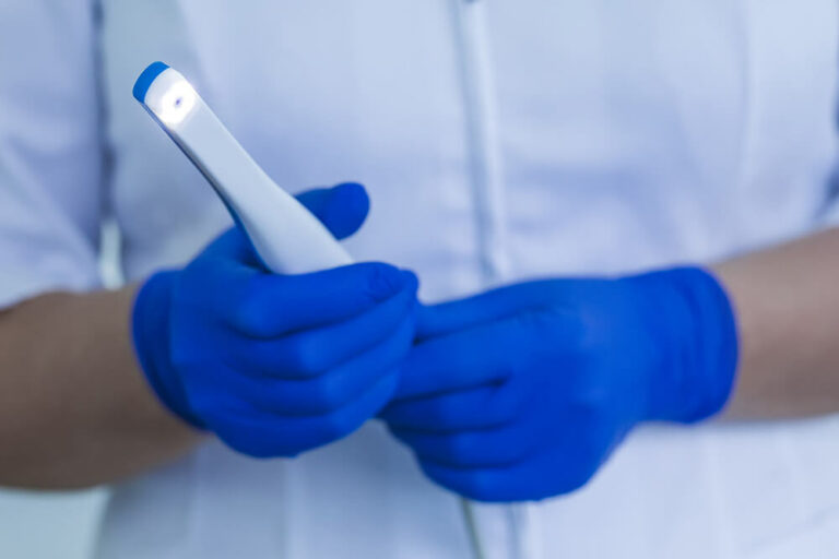 dental worker wearing blue gloves holding intraoral camera